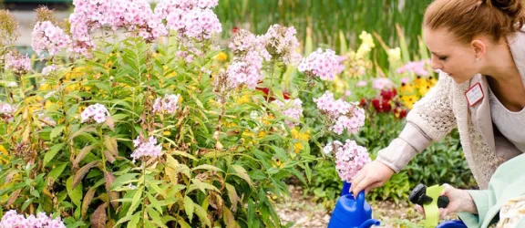 Altenpflegerin und Seniorin gießen Blumen