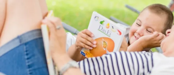 Frau zeigt behindertem Kind ein Buch