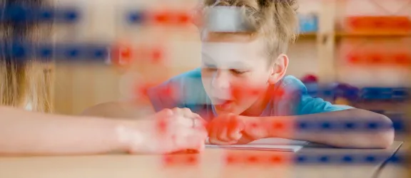 Grundschüler liest mithilfe der Lehrerin