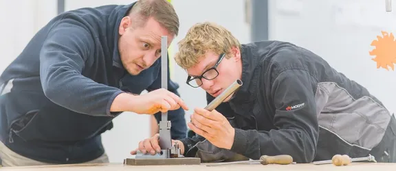 Ausbilder erklärt Azubi etwas bei der Metallverarbeitung