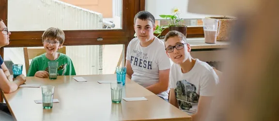 Drei Kinder und ein Erzieher sitzen an einem Tisch