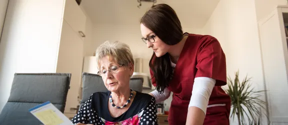Mitarbeiterin der Rummelsberger Diakonie hilft Seniorin mit Formularen