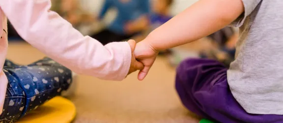 Kinder halten sich an den Händen im Morgenkreis der Kinderkrippe