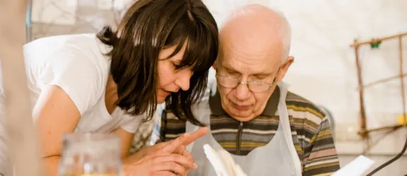 Ein Senior und eine Mitarbeiterin basteln zusammen in der heilpädagogischen Tagesstätte für Senioren