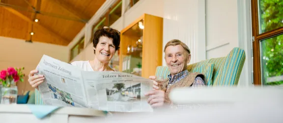 Pflegerin mit Senioren beim Zeitunglesen in der Seniorentagespflege 