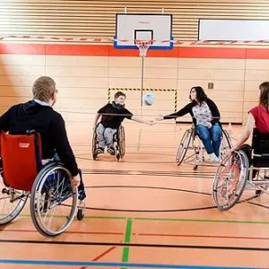 Vier Menschen im Rollstuhl in der Turnhalle