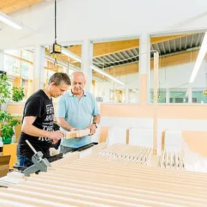Zwei Menschen arbeiten in einer Werkstatt für Menschen mit Behinderung mit Holz