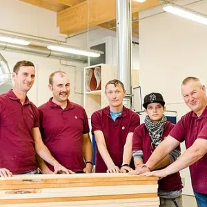 Fünf Menschen stehen in der Holzwerkstatt