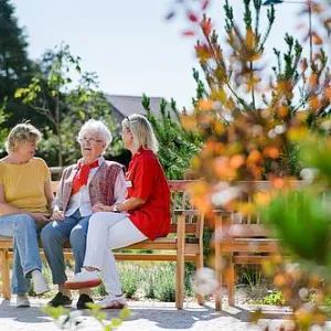 Seniorin mit Besucherin und Mitarbeiterin auf einer Bank vor Seniorenzentrum Gottfried Seiler Feucht