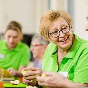 Mitarbeiter und Senioren schneiden gemeinsam Obst bei Tagespflege