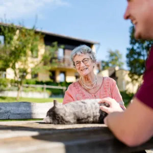 Mitarbeiter des Rummelsberger Stift streichelt mit Seniorin Katze