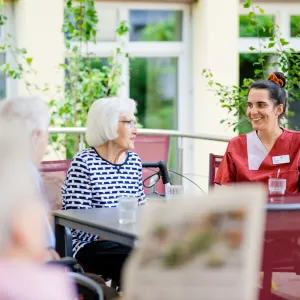 Pflegefachkraft und Bewohnerinnen des Seniorenheims im Gespräch im Garten