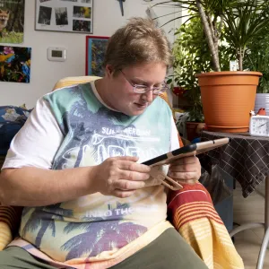 Ein Mann sitzt in einem Sessel mit einem Tablet