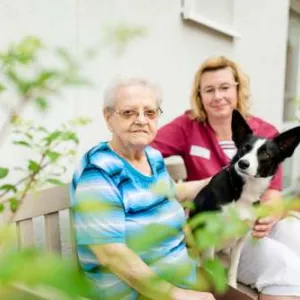 Seniorin auf Bank mit Hund