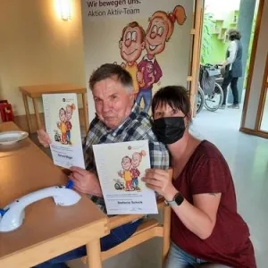 Eine Pflegerin und ein Mann sitzen zusammen an einem Tisch