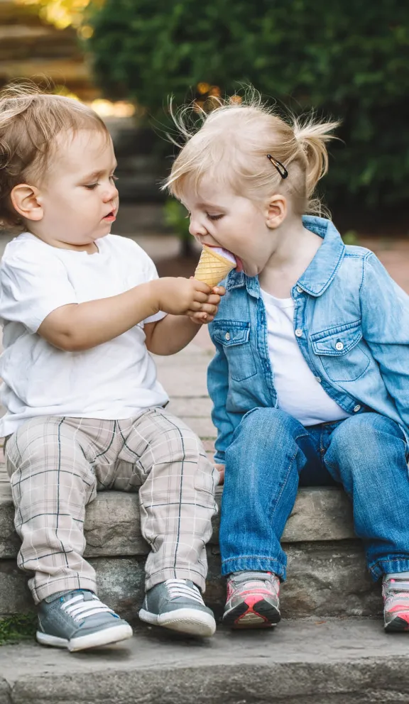 Zwei Kinder, die sich ein Eis teilen.