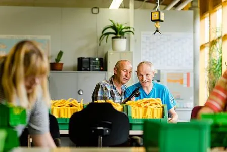 Drei Menschen stehen in der Werkstatt an Tischen