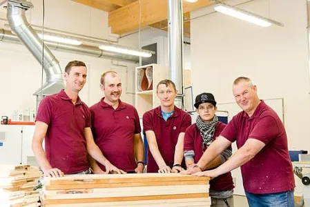 Fünf Menschen stehen in der Holzwerkstatt