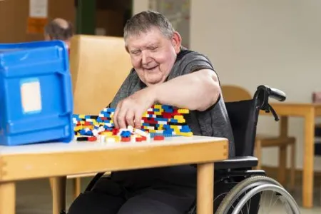 Ein Mann sitzt am Tisch und spielt mit Lego