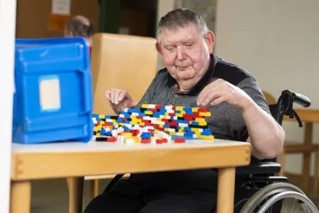 Ein Mann sitzt am Tisch und spielt mit Lego