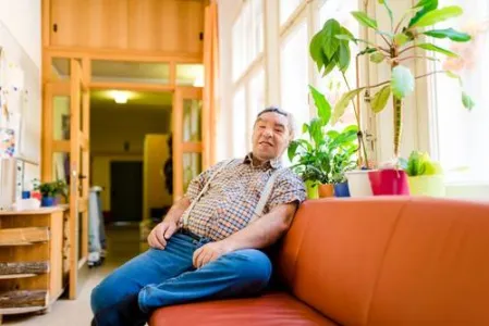 Ein Mann mit Behinderung sitzt auf einem Sofa im Haus Altmühltal