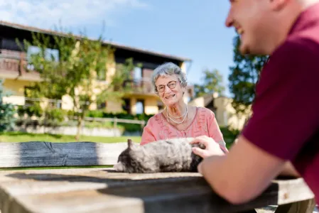 Mitarbeiter des Rummelsberger Stift streichelt mit Seniorin Katze