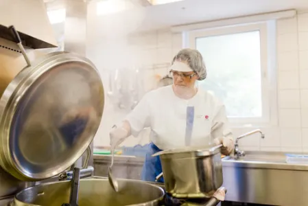 Eine Frau steht in der Küche an einem kochenden Topf