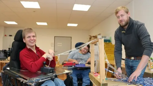 Ein Mann im Rollstuhl webt etwas