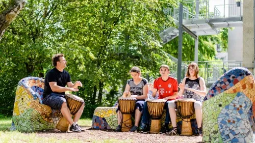 Drei Kinder und ein Lehrer trommeln