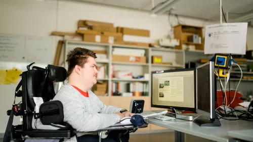 Ein Mann im Rollstuhl sitzt vor einem Bildschirm