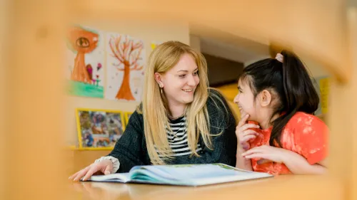 Eine Frau und ein Mädchen sehen sich zusammen ein Buch an.
