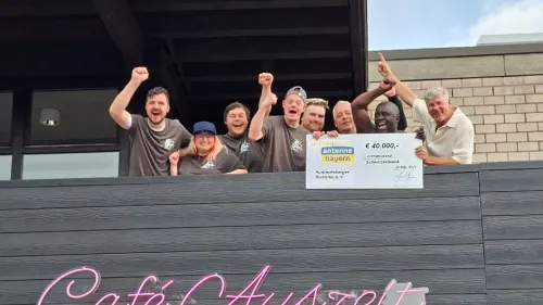 Andreas Ammon, Leiter des Auhofs (r.), Klient*innen und Mitarbeitende freuen sich über die Wiedereröffnung des Cafés. Der Umbau wurde unter anderem durch eine Spende von Antenne Bayern sowie die Förderung durch Aktion Mensch möglich gemacht. 